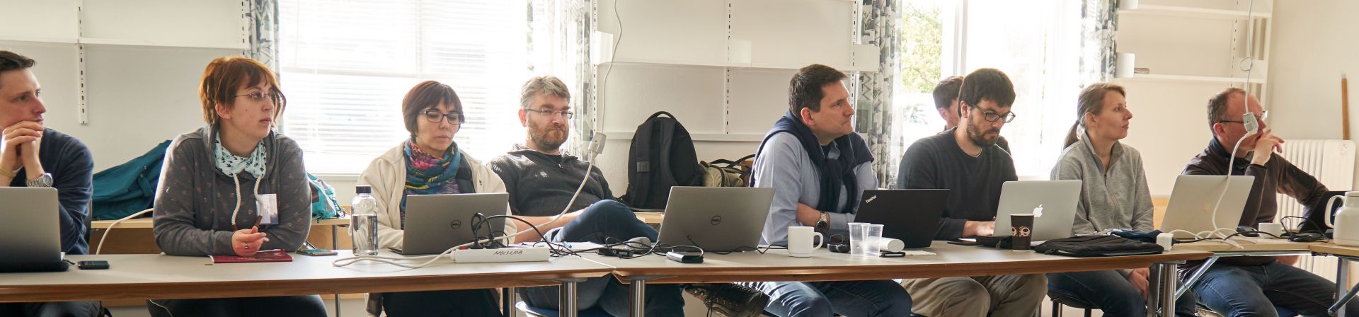 Photo showing workshop participants sitting in a row while listening to a talk on visual analytics and computer graphics in a meeting room.
